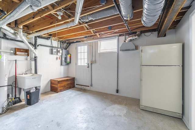 basement featuring electric panel, gas water heater, a sink, and freestanding refrigerator