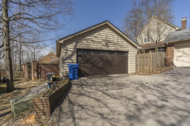 garage featuring driveway and fence