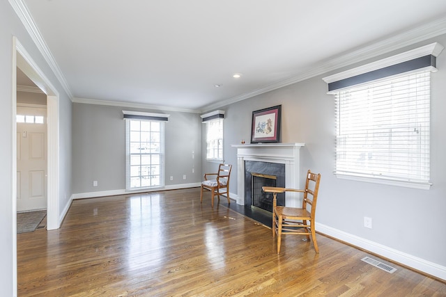 living room featuring visible vents, wood finished floors, a fireplace, and ornamental molding