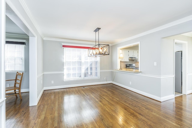 unfurnished dining area with a notable chandelier, ornamental molding, and wood finished floors