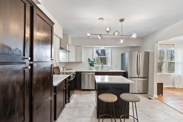 kitchen with dark brown cabinetry, a kitchen island, appliances with stainless steel finishes, and a sink