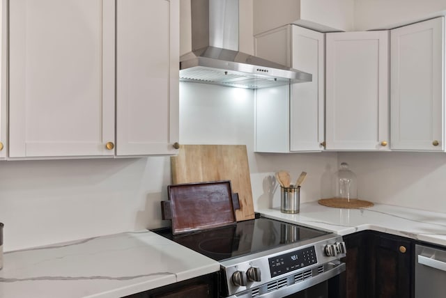 kitchen with white cabinets, appliances with stainless steel finishes, wall chimney range hood, and light stone countertops