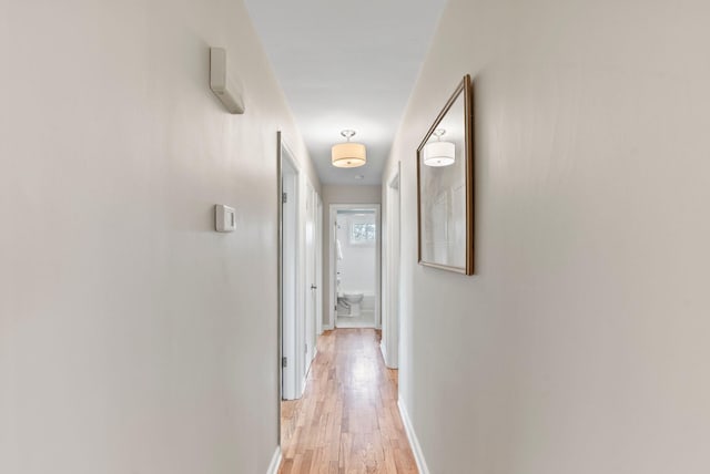 hall featuring light wood-style flooring and baseboards