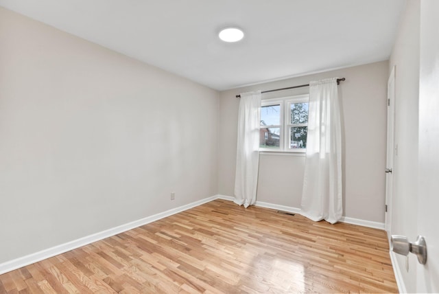 empty room featuring visible vents, light wood-type flooring, and baseboards