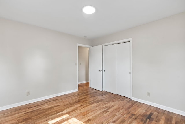 unfurnished bedroom featuring a closet, baseboards, and light wood-style floors