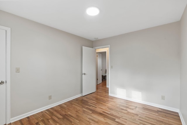 spare room with baseboards and wood finished floors