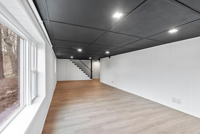 basement featuring stairs, wood finished floors, and visible vents