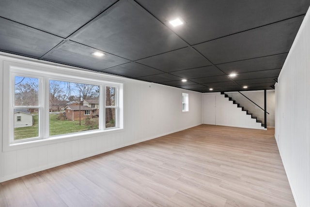 below grade area featuring light wood-style flooring and stairs