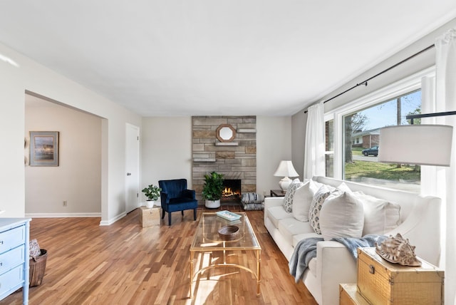 living room featuring a fireplace, light wood-type flooring, and baseboards