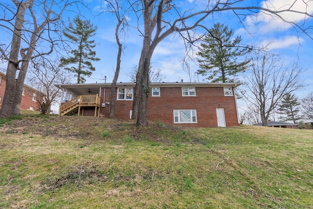 rear view of property featuring brick siding, a lawn, stairs, and a ceiling fan