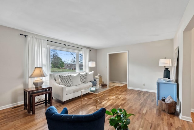 living room featuring visible vents, light wood-style flooring, and baseboards