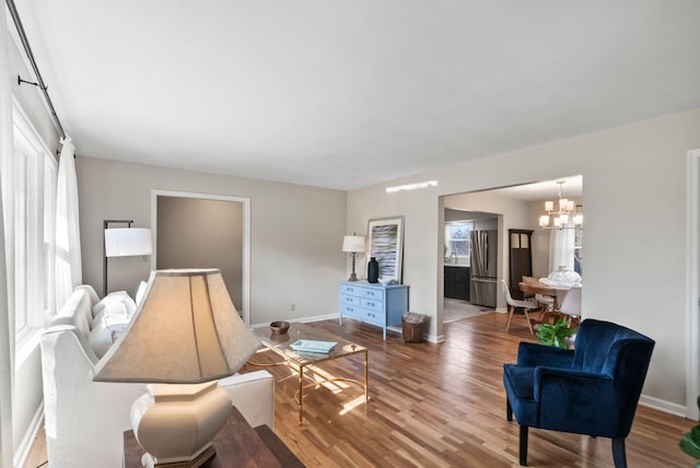 living room with a notable chandelier, plenty of natural light, wood finished floors, and baseboards