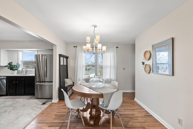 dining space featuring a notable chandelier, light wood-style flooring, visible vents, and baseboards