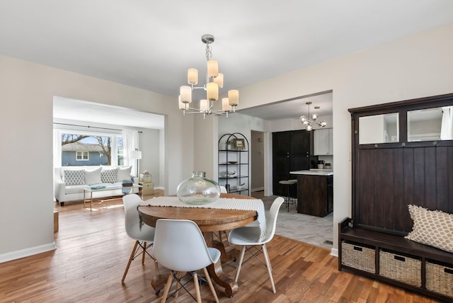 dining space with baseboards, light wood finished floors, and a chandelier