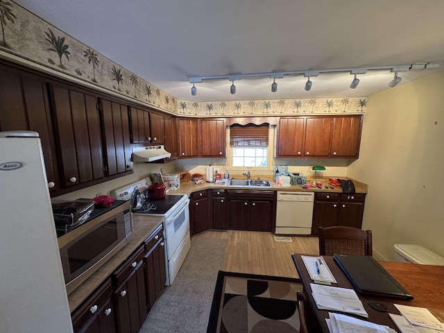 kitchen with under cabinet range hood, white appliances, light wood finished floors, and a sink