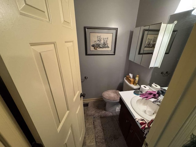 half bath featuring vanity, toilet, and baseboards