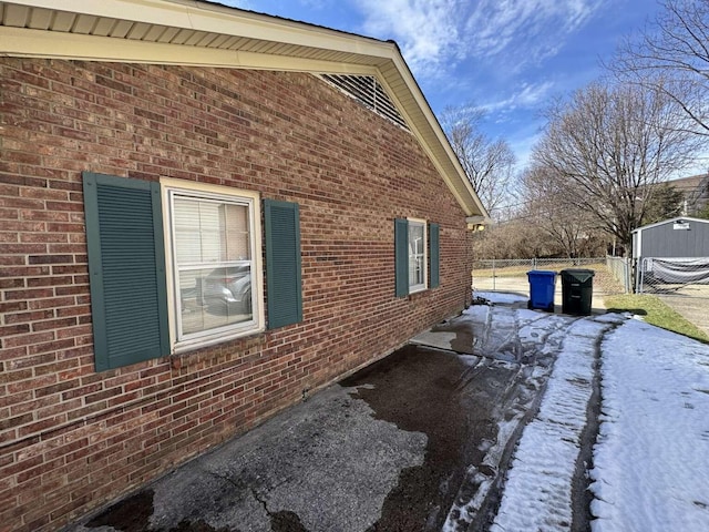 view of side of property featuring fence and brick siding