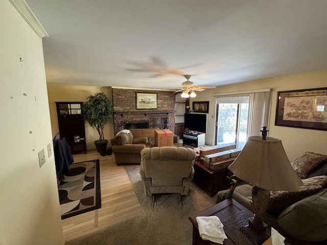 living room with a ceiling fan, a fireplace, and light wood finished floors