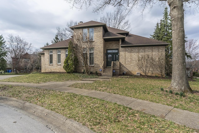 view of front of house with a front lawn, brick siding, and a shingled roof