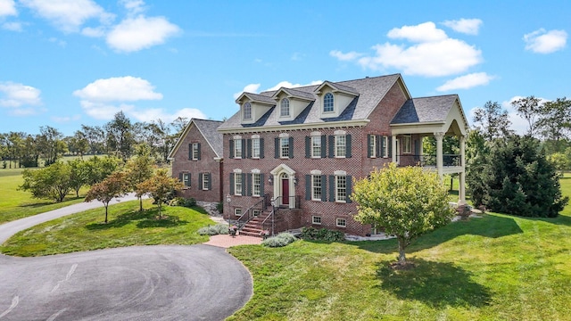 colonial inspired home with brick siding and a front yard