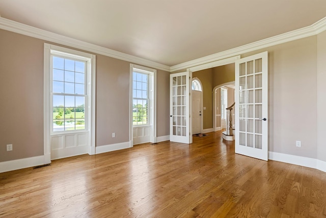 spare room with wood finished floors, crown molding, french doors, and a healthy amount of sunlight