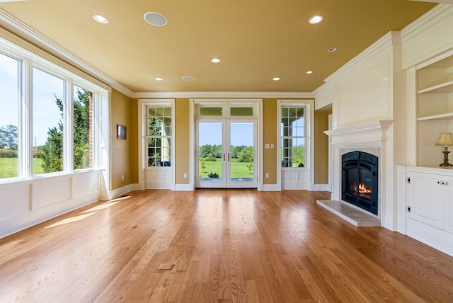 unfurnished living room with a high end fireplace, crown molding, baseboards, light wood-type flooring, and recessed lighting