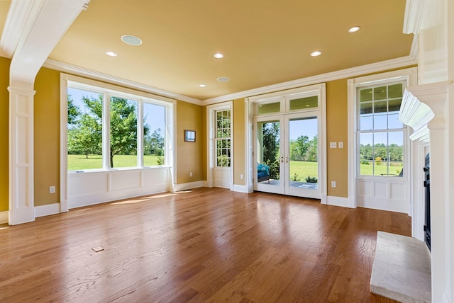 interior space with a healthy amount of sunlight, wood finished floors, and ornamental molding