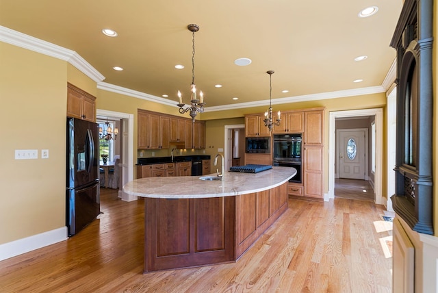 kitchen featuring a notable chandelier, black fridge with ice dispenser, built in microwave, and a sink