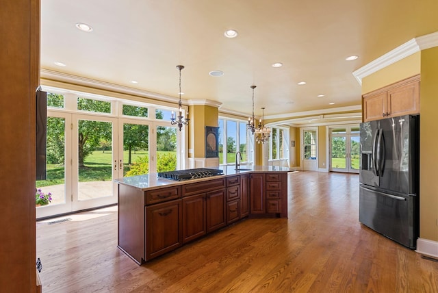 kitchen with ornamental molding, gas cooktop, french doors, an inviting chandelier, and black refrigerator with ice dispenser