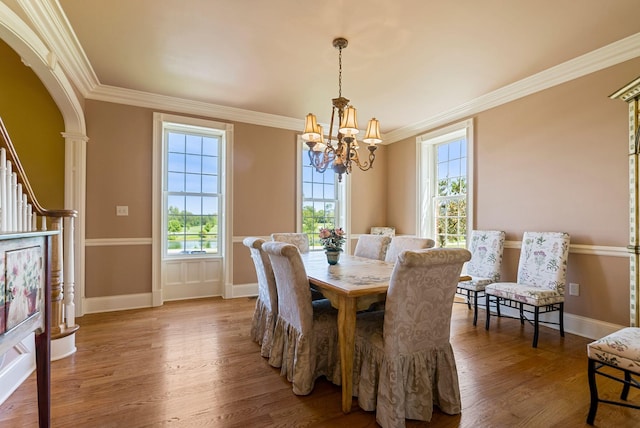 dining area featuring wood finished floors, arched walkways, plenty of natural light, and a chandelier