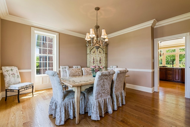 dining area with light wood-type flooring, baseboards, a notable chandelier, and crown molding