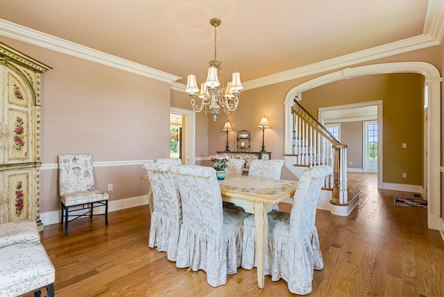 dining room featuring light wood-type flooring, arched walkways, a notable chandelier, and a healthy amount of sunlight