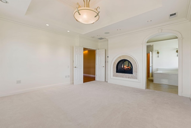 unfurnished living room featuring visible vents, carpet, a tray ceiling, and ornamental molding