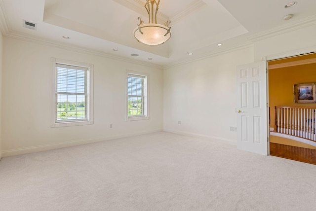 spare room with a tray ceiling, light colored carpet, and visible vents