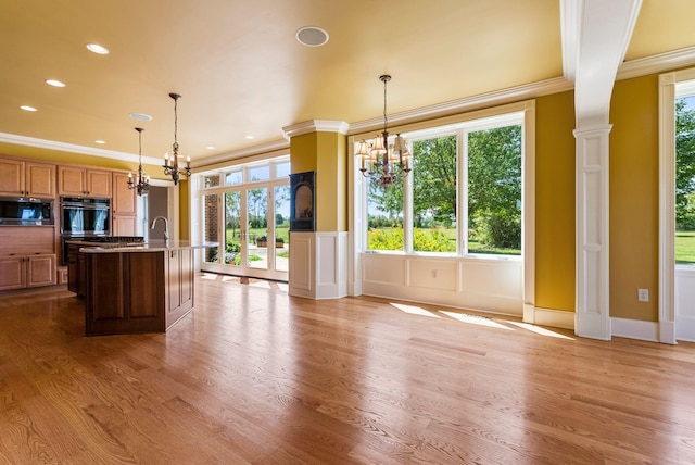 kitchen with double wall oven, a notable chandelier, stainless steel microwave, and light wood-style floors