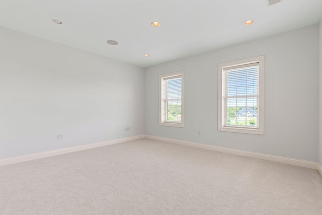 empty room featuring recessed lighting, light colored carpet, and baseboards