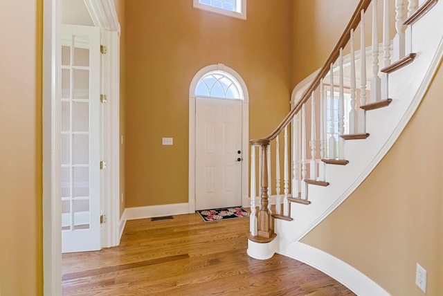 entryway with stairs, visible vents, wood finished floors, and baseboards