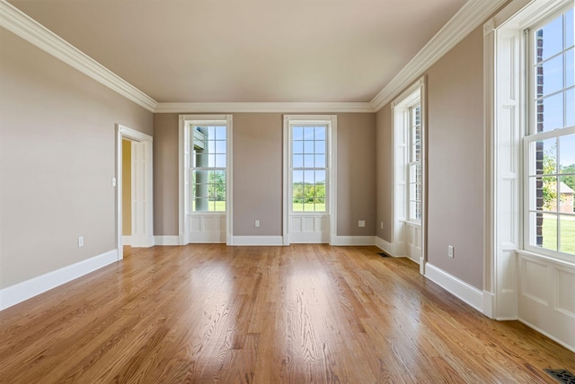 unfurnished room featuring visible vents, a healthy amount of sunlight, light wood-style flooring, and ornamental molding