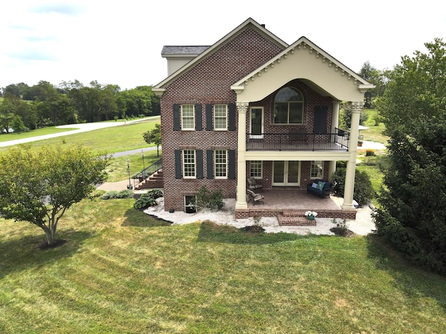 back of property with a patio area, a yard, french doors, and brick siding