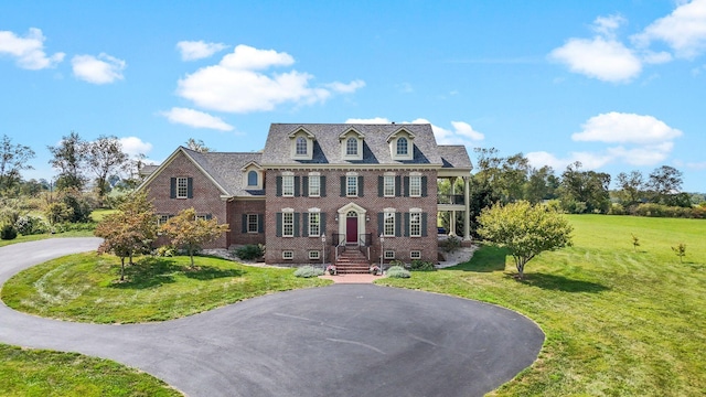 colonial inspired home with brick siding, driveway, and a front yard