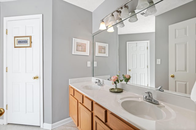 bathroom with a sink, baseboards, and double vanity