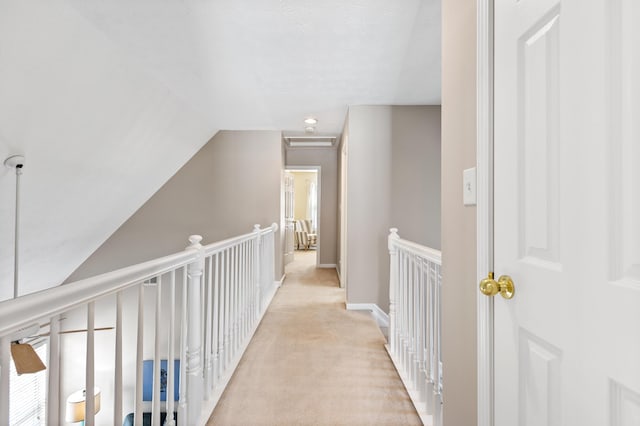 hall featuring baseboards, light carpet, lofted ceiling, and an upstairs landing