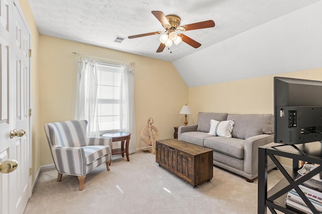 living area featuring baseboards, lofted ceiling, ceiling fan, a textured ceiling, and light carpet