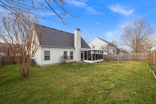 back of house featuring a yard, a fenced backyard, roof with shingles, and a sunroom