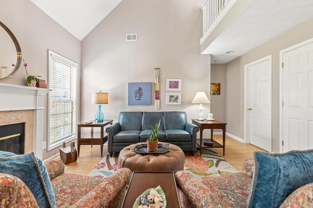 living area featuring visible vents, high vaulted ceiling, wood finished floors, and a high end fireplace