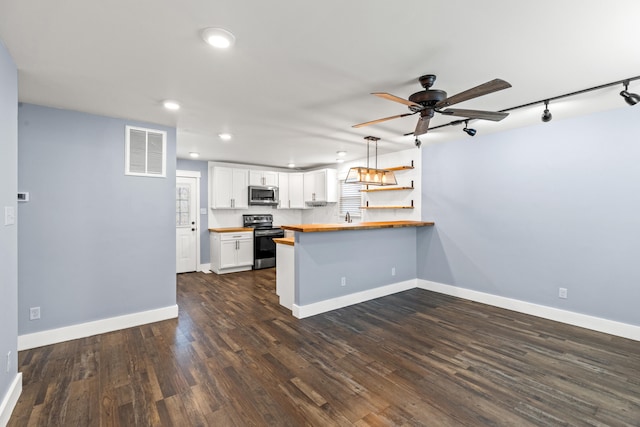 kitchen featuring visible vents, a peninsula, butcher block countertops, range with electric cooktop, and stainless steel microwave