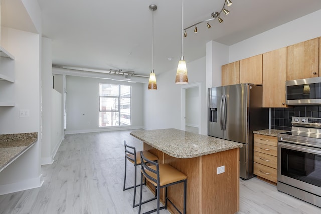 kitchen with a breakfast bar, tasteful backsplash, stainless steel appliances, light wood-style floors, and light stone countertops