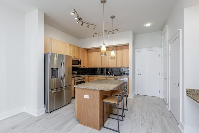 kitchen featuring a breakfast bar, decorative backsplash, light wood finished floors, and stainless steel appliances