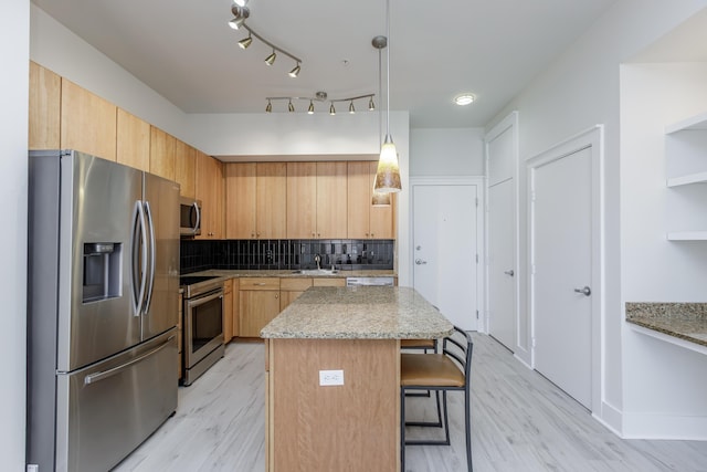 kitchen with a center island, a kitchen bar, decorative backsplash, light wood-style flooring, and appliances with stainless steel finishes