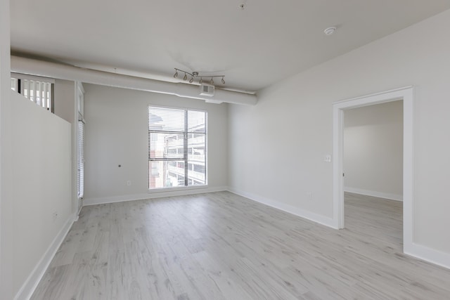 empty room with baseboards and light wood-type flooring